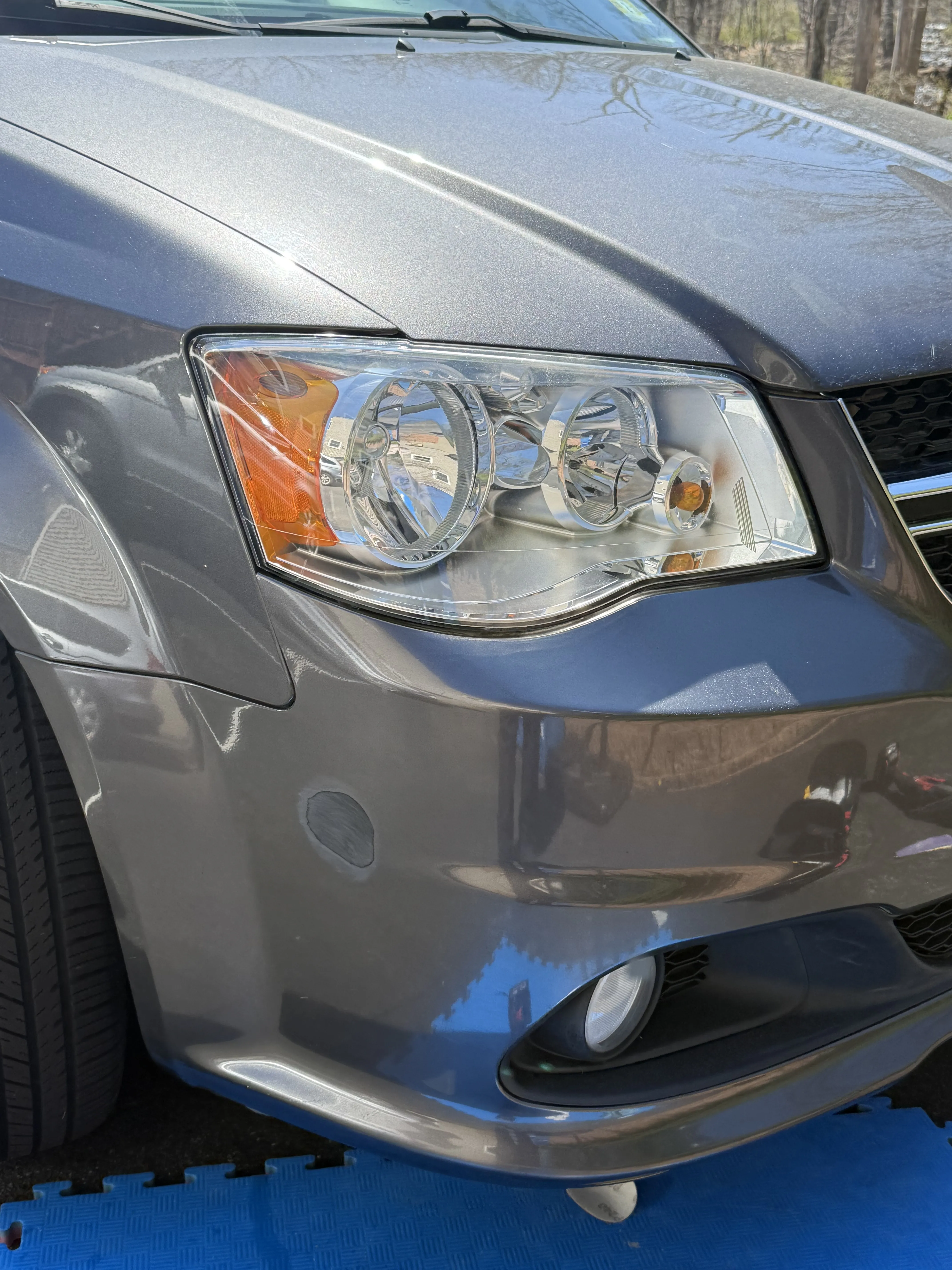 Same Dodge Grand Caravan front bumper after repair, scuffs gone, paint color-matched and smooth.