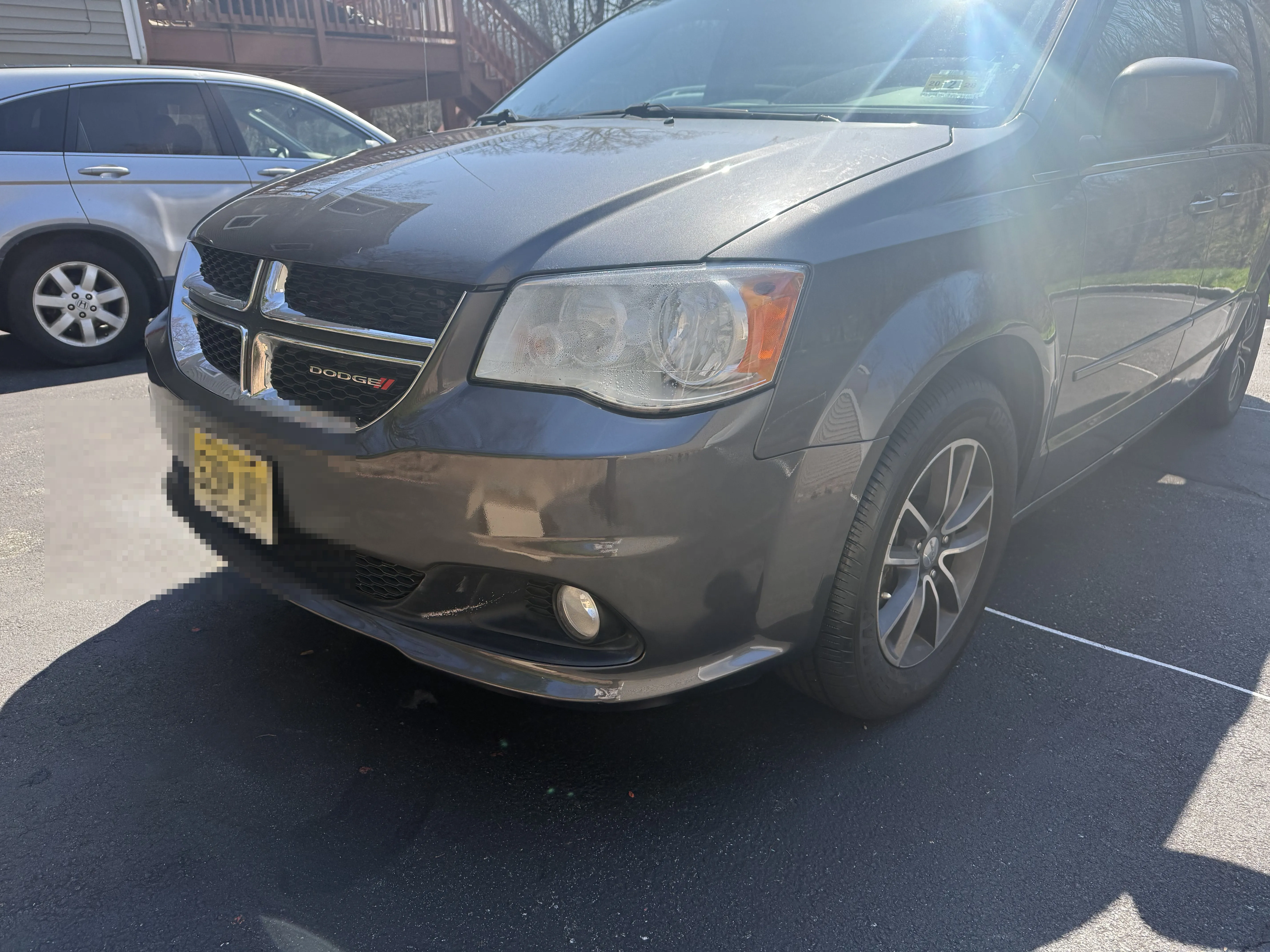 Wider angle of the finished Dodge Grand Caravan front bumper after repair, showing the full front end.